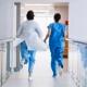 läkare och sjuksköterska springer i en sjukhuskorridor med ryggarna mot kameran.jpg