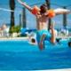 pojke hoppar från poolkant ner i pool med armarna som flygplansvingar.jpg
