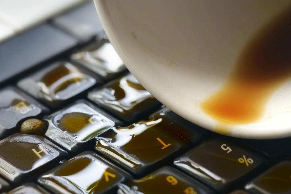 närbild på ett tangentbord med en kaffekopp med utspilt kaffe.jpg