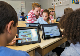 lärare hjälper barn i skolan med uppgifter på ipads.jpg