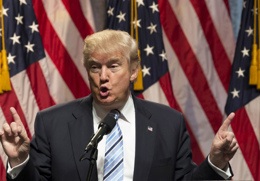 donald trump talar på en scen med bägge händer uppsträckta i lyften.jpg