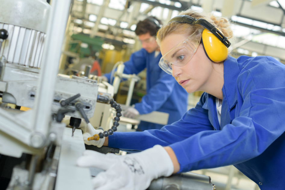 kvinna i blåkläder arbetar vid en industrimaskin.jpg