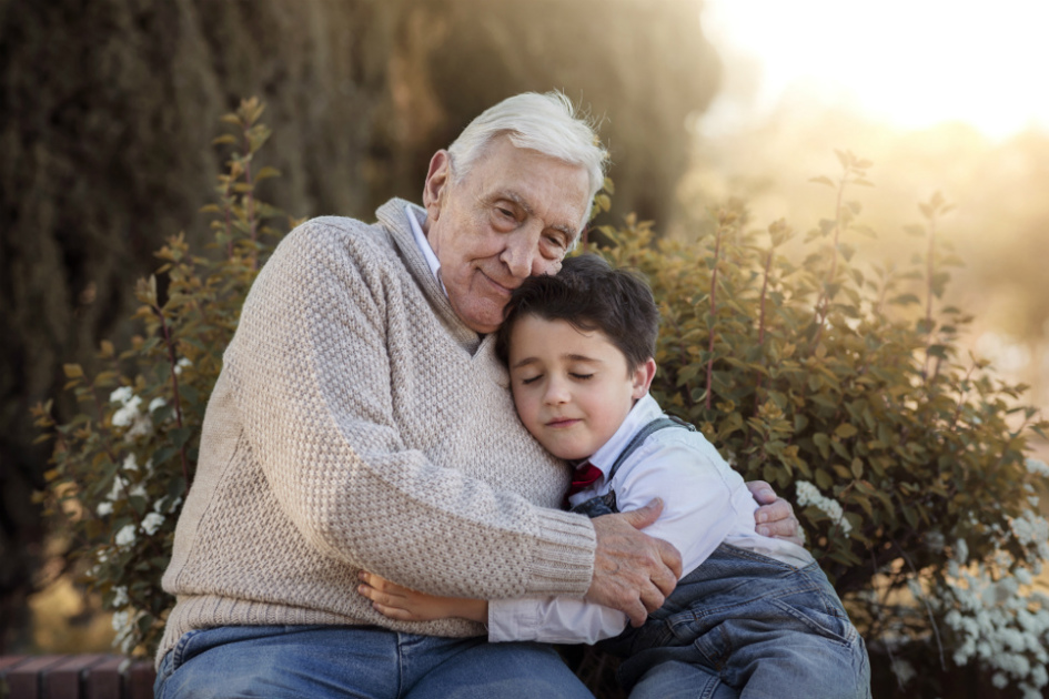 barnbarn och morfar el farfar kramas på en bänk i naturen.jpg