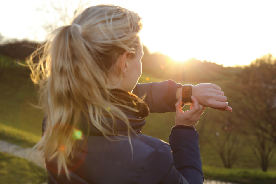 jogginkvinna står i solen och tittar på sin uppkopplade klocka.jpg