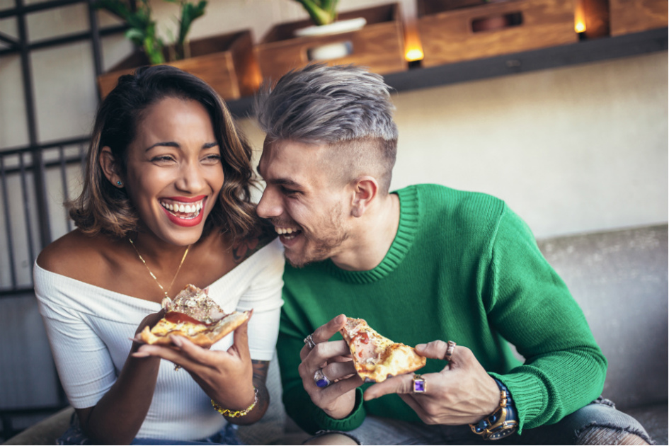 mörk tjej och vit kille äter pizza och är glada.jpg