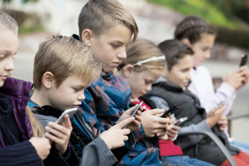 sex barn på rad som tittar i sina mobiler.jpg