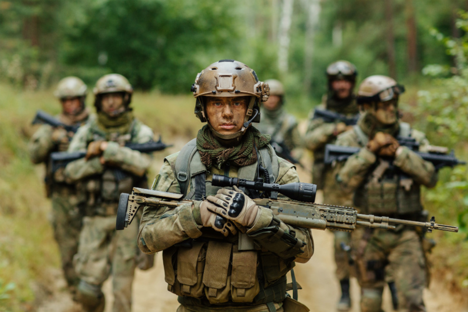 soldater marscherar mot kameran med vapen i famnen på en väg i skogen.jpg