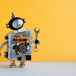 söt robot med skiftnyckel mot gul bakgrund.jpg