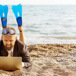 man-med-simfotter-och-dator-på-stranden.jpg