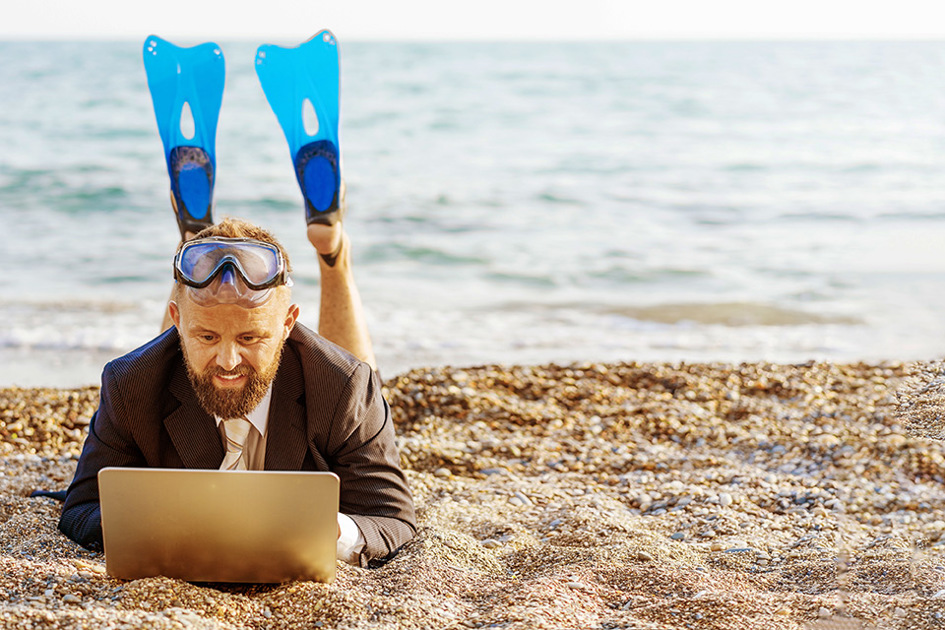 man-med-simfotter-och-dator-på-stranden.jpg