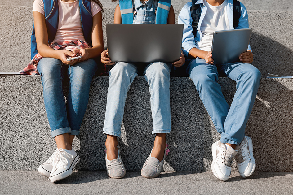 benen syns på tre barn som sitter på mur med dator.jpg