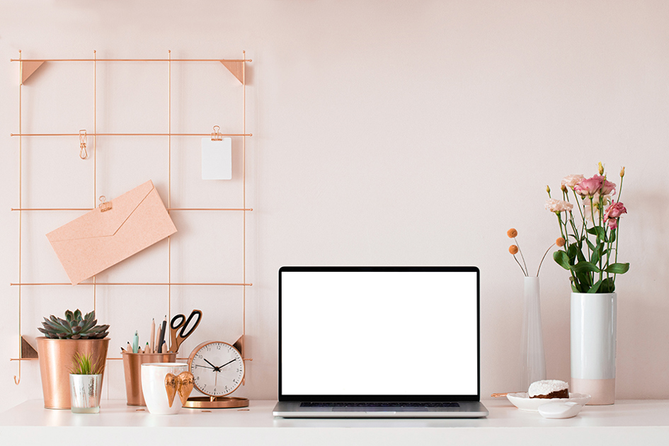 en öppen laptop på ett rosa skrivbord med rosa vägg och lite tillbehör.jpg