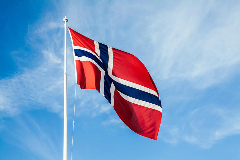 Norsk Flagga På Stång Mot Ljusblå Himmel