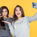 Två Tjejer Posear För En Selfie Mot Gul Bakgrund