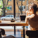 Ung Kvinna Sitter Och Jobbar På Café Och Tittar Ut Genom Fönstret